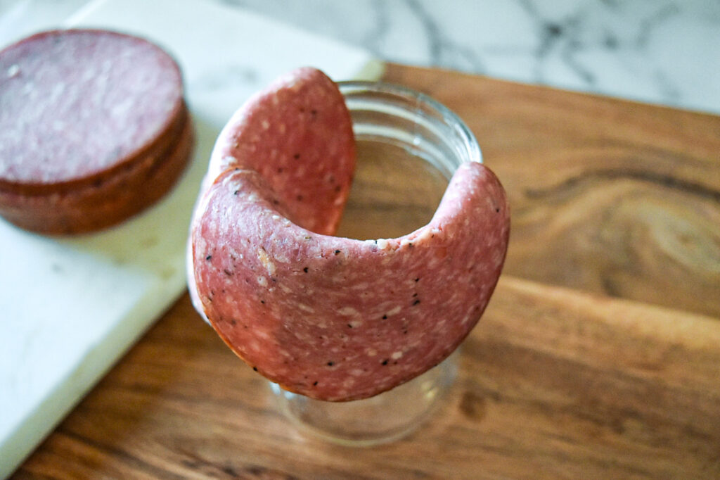 Salami Rose Step 2: Overlap the next slice of salami over the first slice.