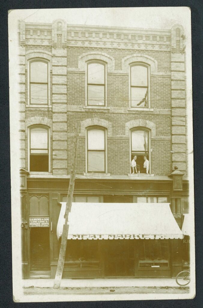 Two woman looking out their apartment window above the meat market at 195 Broadway.