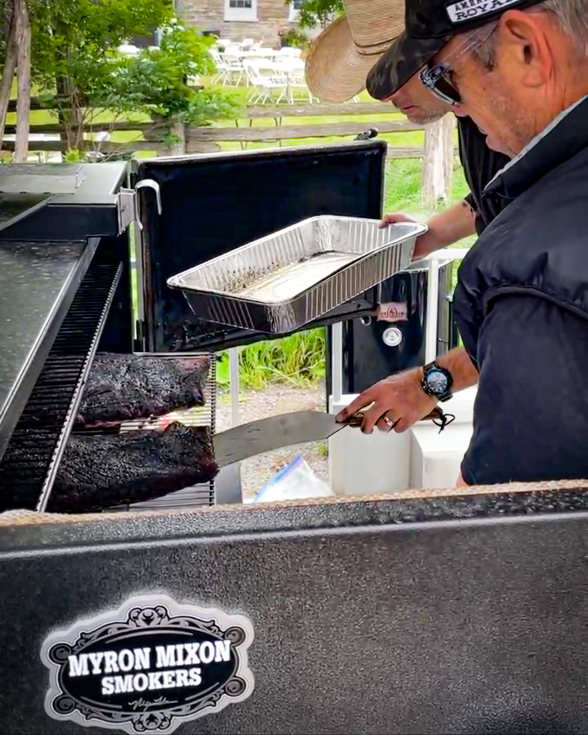 Myron Mixon Smoker being loaded with briskets by 2 professional BBQ competitors
